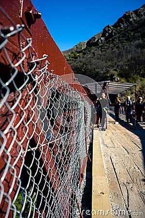 Kawarau Bridge, New Zealand, October 6, 2019: Close-up of the bridge fence with boys in the background preparing to bungee jump Stock Photo