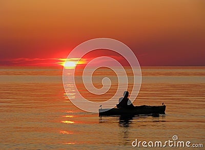 Kayaker on calm water at sunset Stock Photo