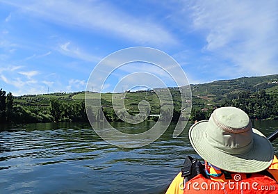 Kayaking in kayak on river with hills and plants and orange vest Stock Photo