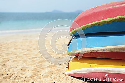 Kayaks stacked on sand beach. Colorful boats in front of sea coast. Stock Photo