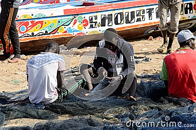 Unidentified Senegalese man sews a fishing net on the coast of Editorial Stock Photo