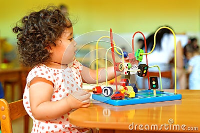 Kazakh curly girl playing in kids development center Stock Photo