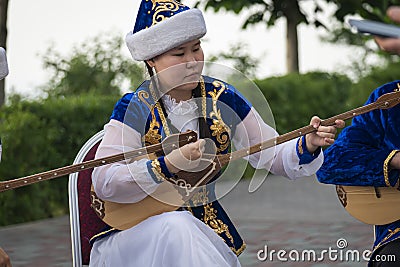 Kazakh woman in blue costume playing dombra Kazakh musical instrument Editorial Stock Photo