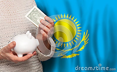 Kazakhstani woman with money bank on the background of Kazakhstan flag. Dotations, pension fund, poverty Stock Photo