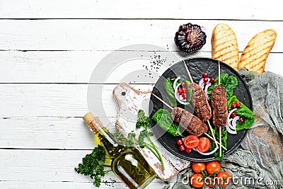 Kebab. Traditional middle eastern, arabic or mediterranean meat kebab with vegetables and herbs. Top view. Stock Photo