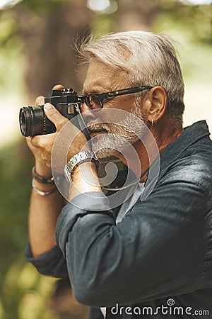 A keen elderly man with a beard takes pictures. Active leisure and hobby that inspires Stock Photo