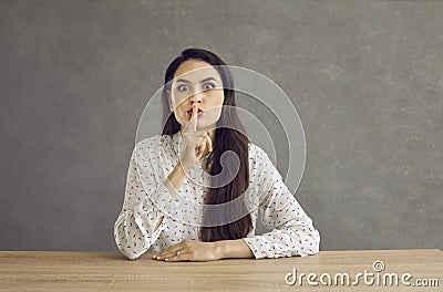 Female teacher keeps finger on lips showing sign of silence, asks students not to make noise. Stock Photo