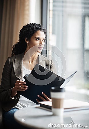 Keeping business moving along. a young businesswoman reading through a business folder in a cafe. Stock Photo