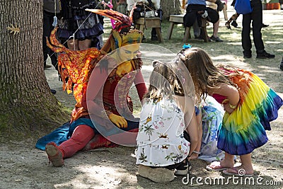 Beautiful girl dressed as fairy at a Renaissance Faire interacting with children in colorful dresses Editorial Stock Photo