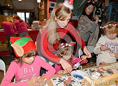 KENTSHIN, POLAND. A woman teaches children to paint a tree toy. Children `s master class in the workshop Editorial Stock Photo