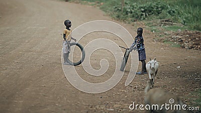 KENYA, KISUMU - MAY 20, 2017: Two african boys playing with tires on the road. Kids having fun together Editorial Stock Photo