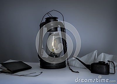 Kerosene lamp, oiler, a notebook on table in the twilight Stock Photo