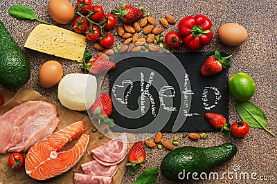 Keto diet food. Healthy low carbs products.Keto diet concept. Vegetables, fish, meat, nuts, seeds, strawberries, cheese on a brown Stock Photo