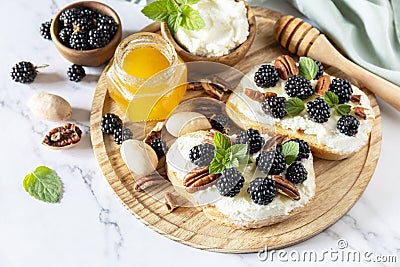 Keto diet sandwiches, snack. Sweet bruschetta with cheese and berries blackberry ricotta and honey on marble table. Healthy Stock Photo