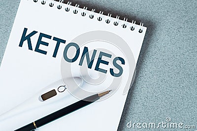 KETONES text written on notepad with a black pencil and electronic thermometre on it on blue surface Medical concept Stock Photo