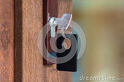 Key with key fob in the keyhole of a closed door Stock Photo