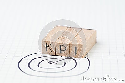 Key Performance Indicator, KPI concept, small wooden stamp combine the acronym KPI with hand draw arrow and target on white grid Stock Photo