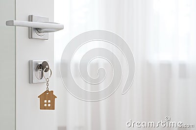 Key with wooden house keyring in open door Stock Photo