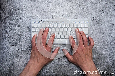 Keyboard with hands on a dark gray background. Asphalt concrete wallpaper. Context, writer, programmer, office work. Stock Photo