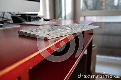 Keyboard is left carelessly on the edge of the desktop and may fall over. Nonchalance attitude to gadgets. Stock Photo