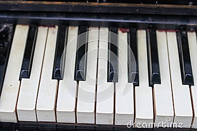 The keyboard of a very old abandoned piano is covered with dust, some keys have dropped, some are absent Stock Photo