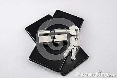 Chrome keychain with keys inserted in a lock on two black mobile phones on white background Stock Photo