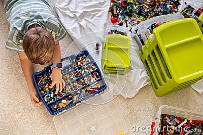 Khabarovsk, Russia, February 18, 2022. Teenager male sorting heap of small Lego pieces into boxes Editorial Stock Photo