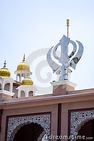 Khanda Sikh holy religious symbol at gurudwara entrance with bright blue sky image is taken at Sis Ganj Sahib Gurudwara in Chandni Stock Photo