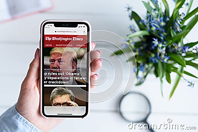 KHARKIV, UKRAINE - April 10, 2019: Apple iPhone X in female hand with washingtontimes.com site on the screen Editorial Stock Photo