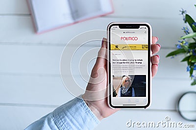 KHARKIV, UKRAINE - April 10, 2019: Woman holds Apple iPhone X with politico.com site on the screen Editorial Stock Photo