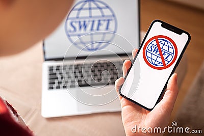 SWIFT blocked, logo close-up on mobile phone screen. Girl use S.W.I.F.T. banking and international technology concept Editorial Stock Photo