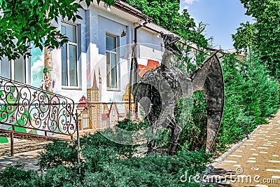 Large metal model of a winged dinosaur on the background of a painted kindergarten building on Kanatna Street in Kherson Editorial Stock Photo