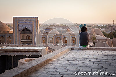 A lonely tourist sitting on the roof of one of houses in Old City of Khiva Editorial Stock Photo