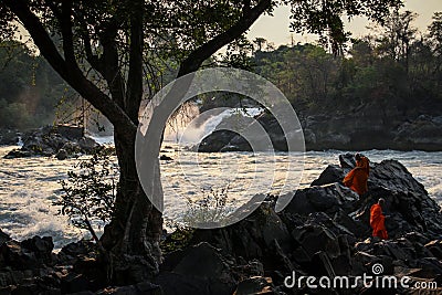 Khone Phapheng Falls at sundown with buddhist monks enjoying the surroundings, Si Phan Don, Champasak Province, Laos Editorial Stock Photo