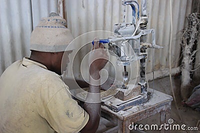 African young male worker at a souvenir factory working with a machine Editorial Stock Photo