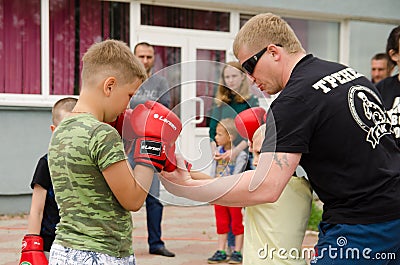 Kickboxing coach shows the boy how to make punch in sparring. Training outdoor in summer Editorial Stock Photo