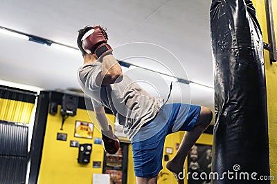 Kickboxing fighter performing Kicks with Knee on punching bag at the gym Stock Photo