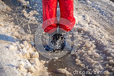 Kid in rainboots jumping in the ice puddle Stock Photo