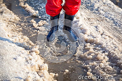 Kid in rainboots jumping in the ice puddle Stock Photo
