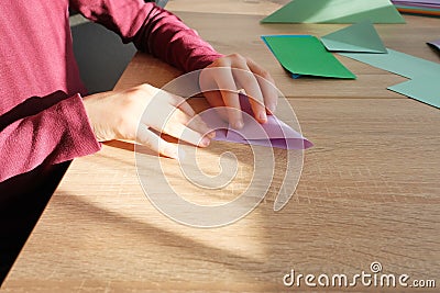 Kid, boy holding model, folded from white paper using Japanese origami technique, concept of crafting crafts, hobbies, games, Stock Photo