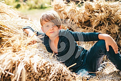 Kid boy lies on the hay. Boy in the hat are preparing for autumn sunny day. Cute boy are getting ready for autumn sale Stock Photo