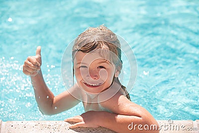 Kid boy swim in swimming pool with thumbs up. Happy little kid boy playing with in outdoor swimming pool on hot summer Stock Photo