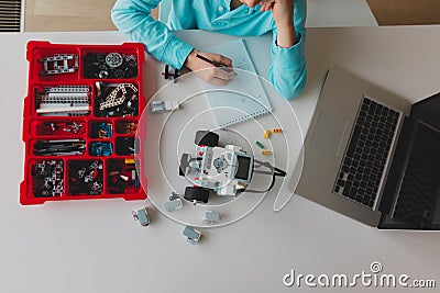 Kid building robot from plastic blocks and programming it with computer Stock Photo