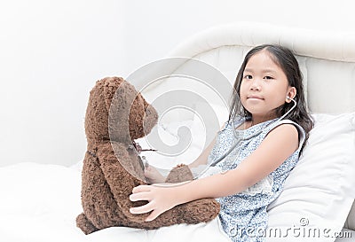 Kid or child playing doctor with stethoscope and teddy bear Stock Photo