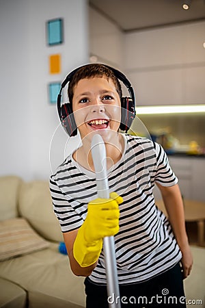 Kid cleaning the floor and listening to the music. He is doing his chore and he is dancing Stock Photo