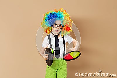 Kid in clown wig and eyeglasses playing catch ball game Stock Photo