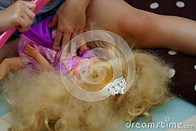 Kid combing hair of princess doll Stock Photo