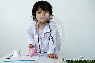 Kid doctor and Medical equipment with pink piggy bank, Saving money for future plan and Health insurance concept Stock Photo