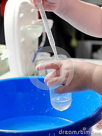 Kid doing scientific experiment at home with liquids holding a test tube and a pasteur pipette. Hands close-up, the concept of Stock Photo