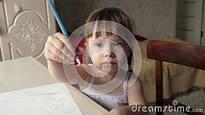 Kid draws on sheet of white paper. Cute little artist girl child crayons in a room at a table. focused smart preschool Stock Photo